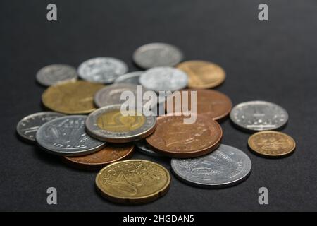 Münzen verschiedener Länder. Eine Streuung von Münzen auf schwarzem Hintergrund. Geringe Schärfentiefe Stockfoto