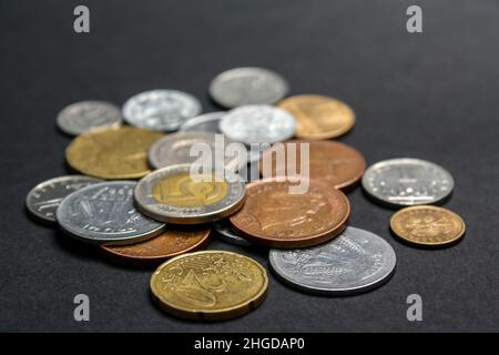 Münzen verschiedener Länder. Eine Streuung von Münzen auf schwarzem Hintergrund. Geringe Schärfentiefe Stockfoto