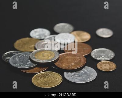 Münzen verschiedener Länder. Eine Streuung von Münzen auf schwarzem Hintergrund. Geringe Schärfentiefe Stockfoto