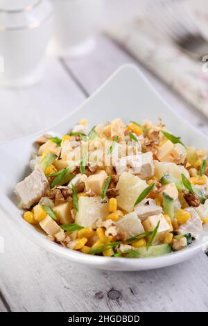 Hühnersalat mit Ananas, Mais und Gurken, mit griechischem Joghurt, zerkleinerten Nüssen und Käse. Stockfoto