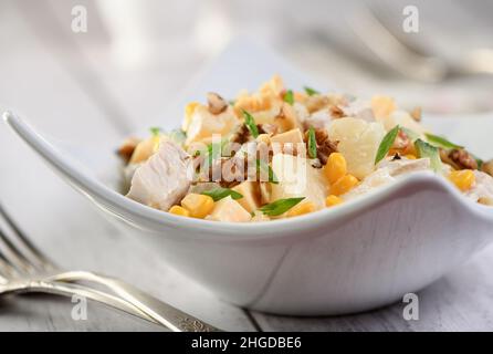 Hühnersalat mit Ananas, Mais und Gurken, mit griechischem Joghurt, zerkleinerten Nüssen und Käse. Stockfoto