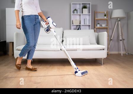 Junges Mädchen Bodenreinigung mit Handstaubsauger Stockfoto