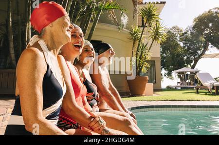 Ältere Menschen lachen fröhlich, während sie sich am Pool entspannen. Fröhliche Senioren genießen ihren Sommerurlaub in einem Spa-Resort. Reife f Stockfoto