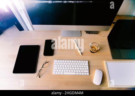 Nahaufnahme des Arbeitsplattes im Büro mit Holztisch und Laptop-Verlegung, Arbeitsplatz. Komfortabler Arbeitsplatz mit Laptop Espresso Smartphone Notizblock Papier Stift Brillen Maus darauf legen. Hochwertige Fotos Stockfoto