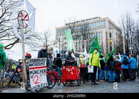 Ein Umweltaktivist verwendet eine Windkraft-Requisite mit einem großen Schild mit der Aufschrift „Sturmisches wachstum? Munchen hat 2 jetzt windrader' (englisch: 'Stormy growth? München hat jetzt zwei Windräder, am 20. Januar 2022 besuchte der Vorsitzende der Grünen Buendnis 90/die Grünen, Vizekanzler und Minister für Wirtschaft und Klimaschutz Robert Habeck den bayerischen Ministerpräsidenten in der Bayerischen Staatskanzlei in München. Vor ihr protestierten Umweltaktivisten für die Windenergie und gegen die 10H-Herrschaft. Die 10H-Regel besagt, dass der Abstand zwischen einer Windenergieanlage und ho Stockfoto