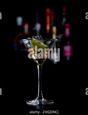 Martini-Cocktail vor verschwommenen Flaschen Stockfoto