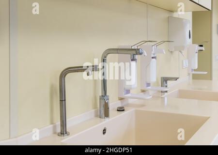 Ellenbogen Seife und antiseptischen Spender oder Desinfektionsmittel Wand zur Händedesinfektion und Wasserhahn Waschbecken mit Wasserhahn Bad oder Klinik montiert Stockfoto