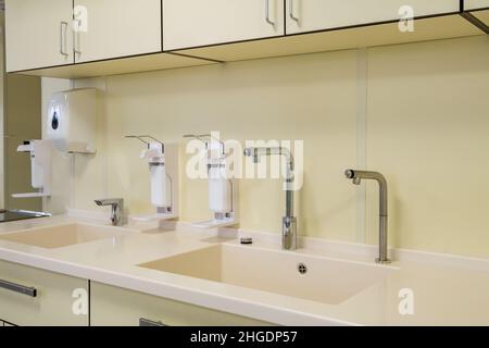 Ellenbogen Seife und antiseptischen Spender oder Desinfektionsmittel Wand zur Händedesinfektion und Wasserhahn Waschbecken mit Wasserhahn Bad oder Klinik montiert Stockfoto