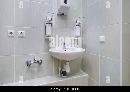 Ellenbogen Seife und antiseptischen Spender oder Desinfektionsmittel Wand zur Händedesinfektion und Wasserhahn Waschbecken mit Wasserhahn Bad oder Klinik montiert Stockfoto