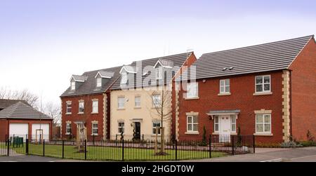 Drei moderne Neubau-Einfamilienhäuser auf einer Wohnsiedlung, blauer Himmel. Stockfoto