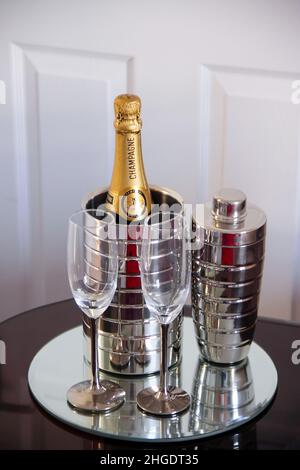 Champage-Flöten, Champagnerflasche im Weinkühler mit Cocktailshaker auf einem verchromten Disc-Tablett, Stockfoto