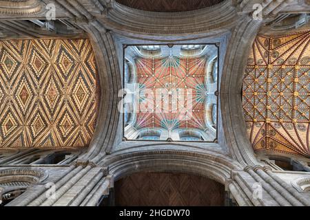 Die bemalte Holzdecke unter dem zentralen Turm in der mittelalterlichen Kathedrale von Peterborough, England, mit der bemalten Kanzeldecke auf der rechten Seite. Stockfoto