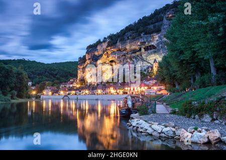 La Roque Gageac Landschaft lange Exposition vor Sonnenaufgang mit dem Fluss Dordogne und reflektierten Dorflichter und Klippen im Wasser Stockfoto