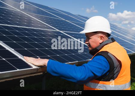 Solaranlagenarbeiter inspiziert Photovoltaikpaneele auf Schäden Stockfoto