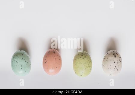 Vier pastellfarbene gesprenkelte Eier; blau, rosa, grün und weiß; Auf weißem Hintergrund Stockfoto