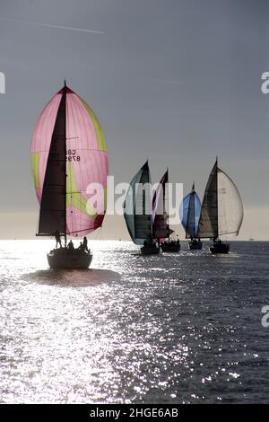 Yachten laufen nach unten mit symmetrischen Spinnakern, die bei leichtem Wind eingesetzt werden. Rennen von Cowes nach Cherbourg Stockfoto