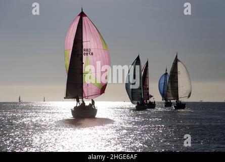 Yachten laufen nach unten mit symmetrischen Spinnakern, die bei leichtem Wind eingesetzt werden. Rennen von Cowes nach Cherbourg Stockfoto