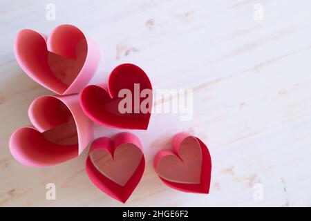 Pinke Papierherzen auf hellem Holzhintergrund mit Kopierraum Stockfoto