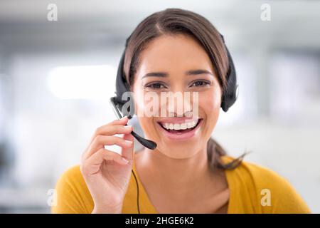Sie freut sich darauf, Ihnen zu helfen. Porträt eines attraktiven jungen Kundendienstmitarbeiters, der ein Headset trägt. Stockfoto