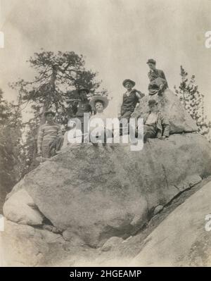 Antike Fotografie aus dem Jahr 1900, viktorianische Frauen und Männer auf einer Wanderung im Freien posieren für ein Foto auf einem großen Felsbrocken. Genaue Lage unbekannt, USA. QUELLE: ORIGINALFOTO Stockfoto