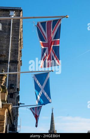 Die Flaggen Union Jack und Scottish Saltyre hängen vor den Edinburgh City Chambers auf der High Street in Edinburgh. Stockfoto