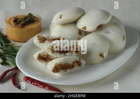 Gefüllter, gedämpfter Reiskuchen mit Hühnchen. Gedämpfter Reiskuchen, gefüllt mit Chicken Masala. Gemeinhin als Huhn gefüllt Idli in Kerala. Serviert mit Kokosnuss Stockfoto