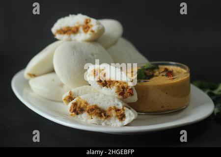 Gefüllter, gedämpfter Reiskuchen mit Hühnchen. Gedämpfter Reiskuchen, gefüllt mit Chicken Masala. Gemeinhin als Huhn gefüllt Idli in Kerala. Serviert mit Kokosnuss Stockfoto