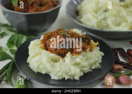 Zerschmetterte Tapioka mit grünen Chilischoten und Schalotten, serviert mit Chicken Gravy. Beliebtes Gericht von Kerala, auch bekannt als Kappa Vevichathu und Kozhi-Kurie. Sh Stockfoto