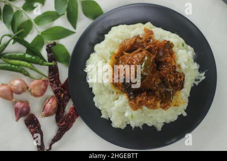 Zerschmetterte Tapioka mit grünen Chilischoten und Schalotten, serviert mit Chicken Gravy. Beliebtes Gericht von Kerala, auch bekannt als Kappa Vevichathu und Kozhi-Kurie. Sh Stockfoto