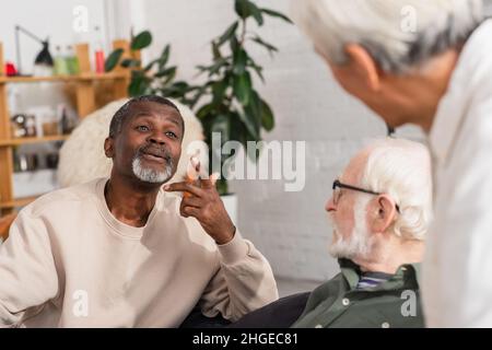 afroamerikanischer Mann, der zu Hause mit verschwommenen Freunden spricht Stockfoto