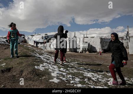 Beqaa Valley, Libanon. 20th Januar 2022. Syrische Flüchtlingskinder spielen in einem Lager im Bekaa-Tal mit Schneeflocken. Syrische Flüchtlinge kämpfen angesichts des extremen Winterwetters nach heftigem Regen und Schneefall darum, ihre Zelte warm zu halten. Quelle: Marwan Naamani/dpa/Alamy Live News Stockfoto