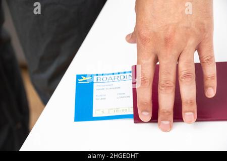 Eine Aufnahme eines Mannes, der ihren Pass und ihre Bordkarte in einem Flughafen hält Stockfoto