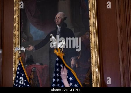 Washington, USA. 20th Januar 2022. Ein Arbeiter hebt die US-Flagge vor einer Pressekonferenz der Sprecherin des Repräsentantenhauses der Vereinigten Staaten, Nancy Pelosi (Demokratin von Kalifornien), am Donnerstag, den 20. Januar 2022, im US-Kapitol in Washington, DC. (Kredit: Rod Lampey/Pool/Sipa USA) Kredit: SIPA USA/Alamy Live News Stockfoto