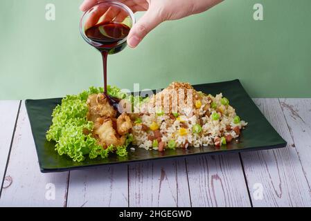 Traditionelle chinesische Küche Gebratener Reis Yang Zhou mit Abalone-Pilz und Teriyaki-Sauce in schwarzem Tablett auf Holztisch Hintergrund Stockfoto