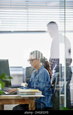 Ihre Arbeit erledigen. Eine kurze Aufnahme eines attraktiven jungen Designers, der an einem pc arbeitet. Stockfoto