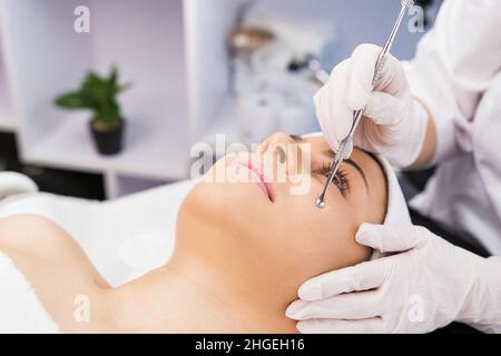 Schöne Frau liegt auf dem Massageliegen und bekommen Verfahren gegen Akne in der Kosmetologie Klinik, Beauty-Konzept. Stockfoto