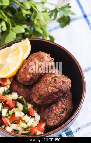 Gebratenes Hackfleisch Kofta oder Kebabs mit Gemüsesalat in einer Schüssel serviert. Nahaufnahme. Konzept der Speisen aus dem Nahen Osten. Stockfoto