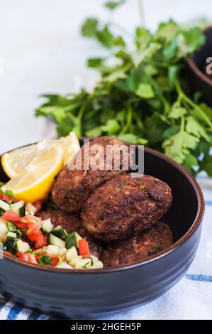 Gebratenes Hackfleisch Kofta oder Kebabs mit Gemüsesalat in einer Schüssel serviert. Nahaufnahme. Konzept der Speisen aus dem Nahen Osten. Stockfoto