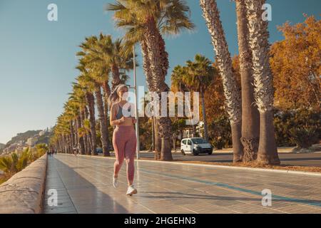 Sportliche glückliche Frau, die aktiv am Wasser läuft Stockfoto