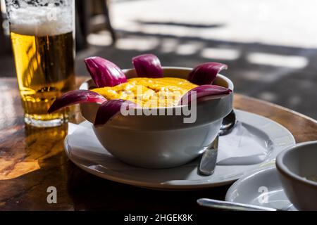 Köstliche traditionelle Gerichte aus Gran Canaria, Gofio Escaldado, werden mit rohen roten Zwiebeln serviert. Stockfoto