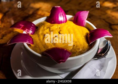 Köstliche traditionelle Gerichte aus Gran Canaria, Gofio Escaldado, werden mit rohen roten Zwiebeln serviert. Stockfoto