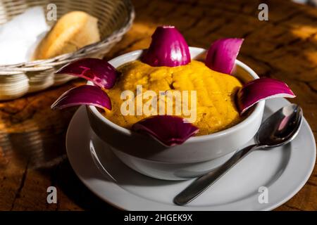 Köstliche traditionelle Gerichte aus Gran Canaria, Gofio Escaldado, werden mit rohen roten Zwiebeln serviert. Stockfoto