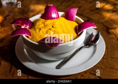 Köstliche traditionelle Gerichte aus Gran Canaria, Gofio Escaldado, werden mit rohen roten Zwiebeln serviert. Stockfoto