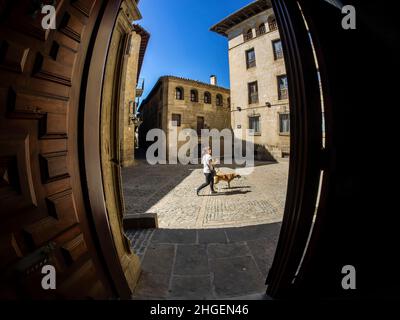 Eine Frau geht mit ihrem Hund auf einem Platz in der aragonesischen Stadt Sos del Rey Católico. Stockfoto
