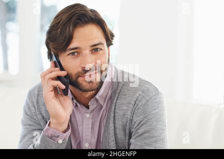 Per Handy in Kontakt bleiben. Ein hübscher junger Mann, der sein Handy benutzt. Stockfoto