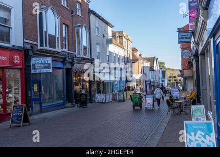 Shopper genießen die Geschäfte entlang der Abbey Gate Street in Bury St Edmunds.Bury St Edmunds ist eine Marktstadt im Osten Englands, die für ihre historischen Gebäude und wohlhabenden Straßen berühmt ist. Die Stadt verfügt über gut erhaltene Gebäude wie die Abbey Gardens und die St. Edmundsbury Cathedral. Stockfoto