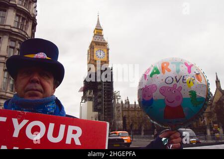 London, Großbritannien 19th. Januar 2022. Der Aktivist Steve Bray hält auf dem Parliament Square einen „Party's Over“-Ballon. Die Demonstranten versammelten sich vor dem Parlament, als Boris Johnson mit der Fragestunde der Premierministers und Rufen zum Rücktritt wegen der Lockdown-Parteien in der Downing Street konfrontiert wurde. Stockfoto