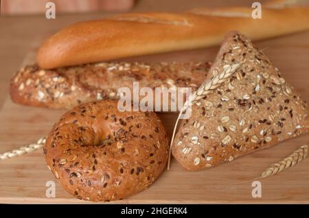 Verschiedene Brotsorten, frisches Gebäck in der Bäckerei. Brot mit Sesam, Getreide, Samen. Verschiedene Formen und Arten von Rollen. Weizenohren auf einem W Stockfoto