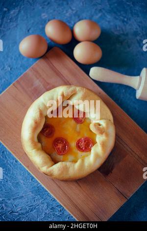 Pizza Mit Tiefem Gericht. Сhicago Pizza 4 Käse, getrocknete Kirschtomaten. Essen auf einem Holzteller, Nudelholz und 4 Eier, Rezept Pie Pizza. Festliches Gebäck auf einem Stockfoto