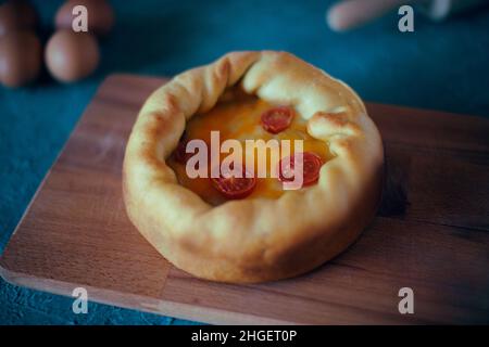 Pizza Mit Tiefem Gericht. Сhicago Pizza 4 Käse, getrocknete Kirschtomaten. Essen auf einem Holzteller, Nudelholz und 4 Eier, Rezept Pie Pizza. Festliches Gebäck auf einem Stockfoto